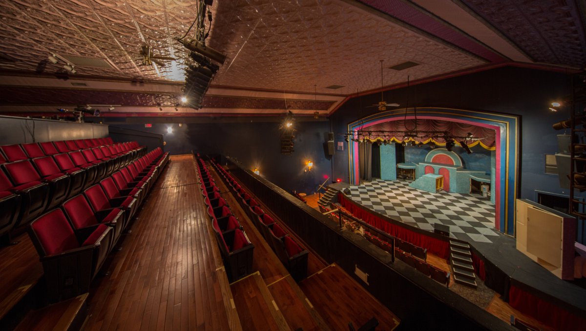 Interior of theater from balcony, looking down onto black-and-white checkered stage