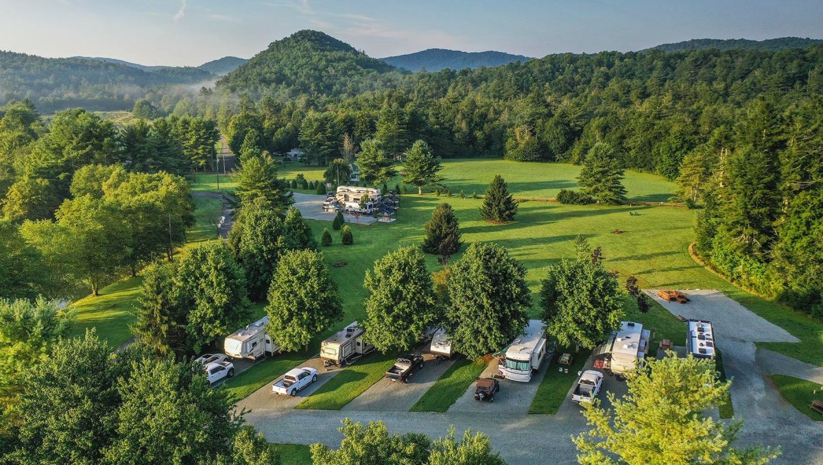 Aerial of RVs, fields and evergreen trees at Pineola Campground during daytime.