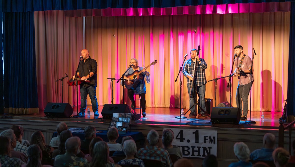 Band playing onstage while crowd looks on at cultural center.