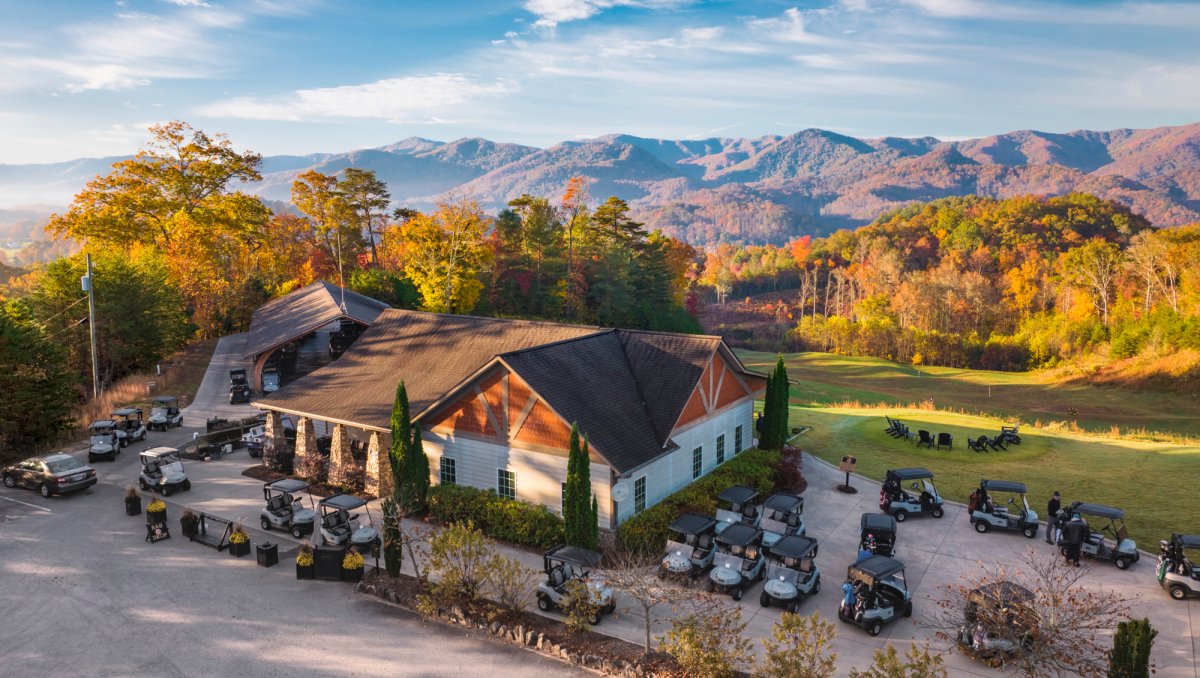 Aerial of golf clubhouse with beautiful mountains in background during fall.