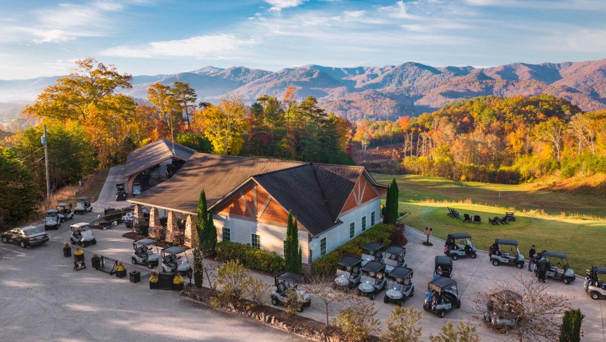 Aerial of golf clubhouse with beautiful mountains in background during fall.