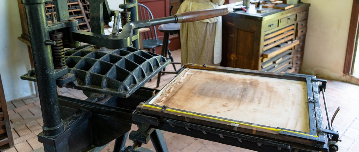 Antique printing press inside old clerk's office with demonstrator in background