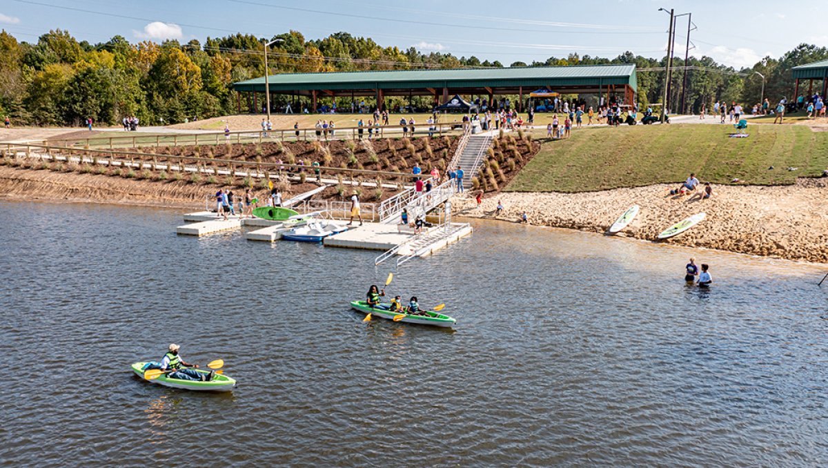 Aerial of people kayaking in water with canoe launches and park in background during daytime