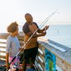 Grandfather and granddaughter fishing off pier on NC coast.