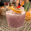 Purple cocktail on bar with diners in background