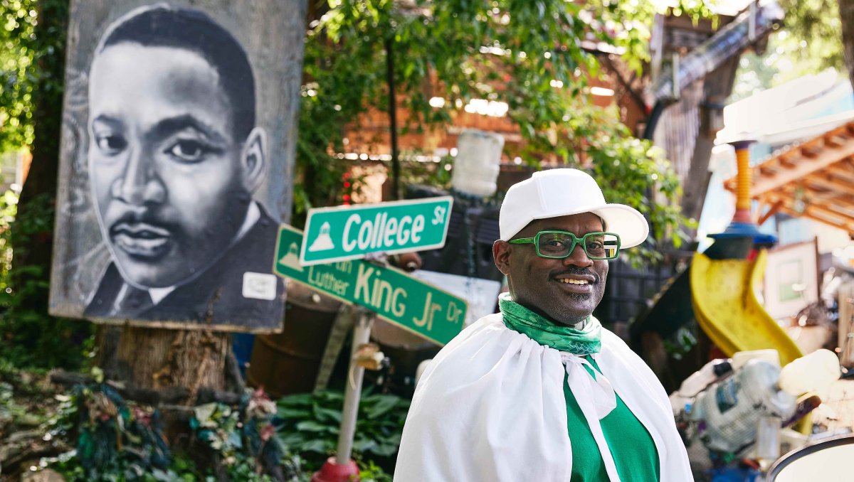 Black history tour guide posing for camera in front of Dr. Martin Luther King Jr. art.