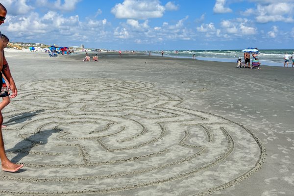 Man walking on sand maze in middle of beach