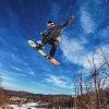 Snowboarder in midair after making jump with snow flying behind him