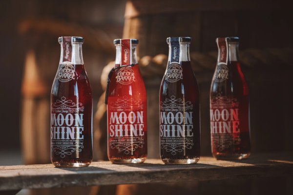 Four bottles of moonshine sitting on a wood counter