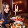 Woman holding cocktail and admiring seafood tower on table in front of her.