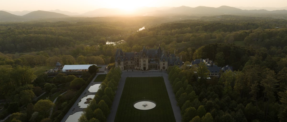 Aerial of vast Biltmore grounds and estate with mountains in background