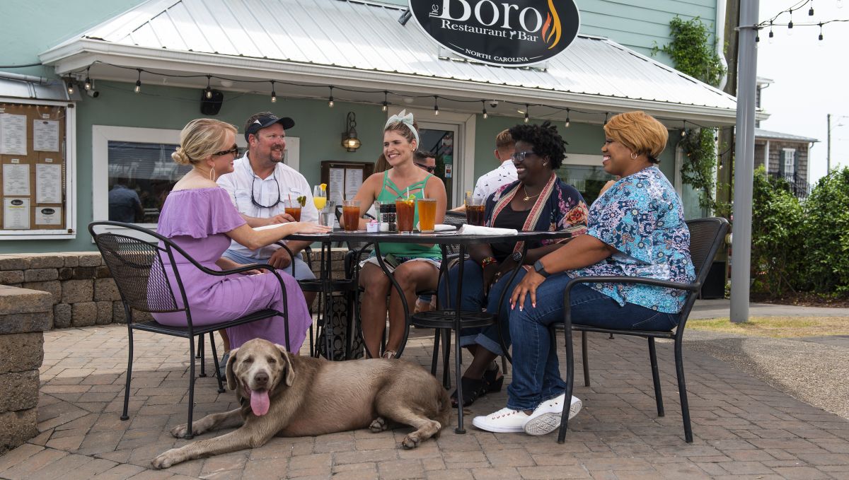 Group of friends sitting around a table with drinks, a 