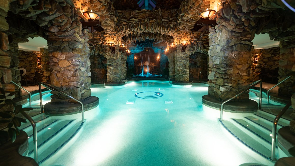 Subterranean spa with cavernous walls with clear blue pool in center