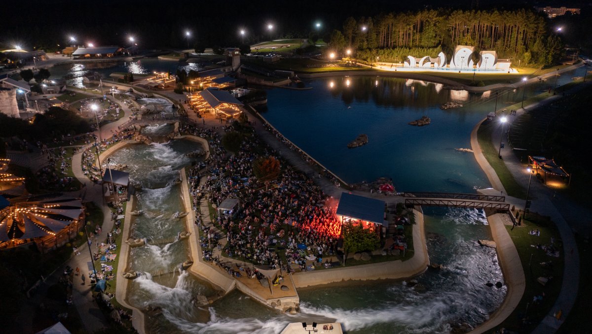Aerial shot of outdoor whitewater center with tons of people on lawn watching live music