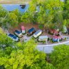Aerial shot of tiny houses making up tiny house hotel, surrounded by tall bright green trees during daytime