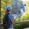 Woman looking onto waterfall from hiking trail surrounded by trees