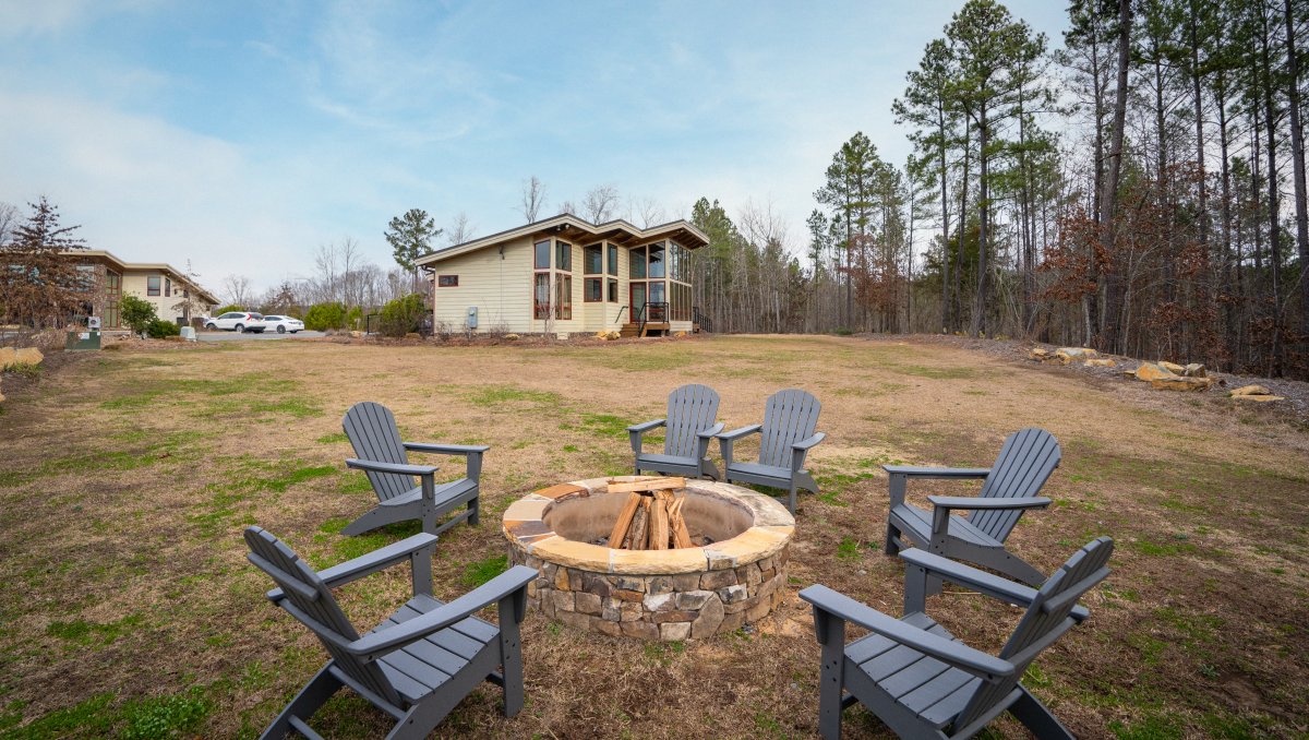 Adirondack chairs around fire pit on farm's grounds with cabin in background