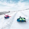 Two kids riding down hill in snow tubes during daytime