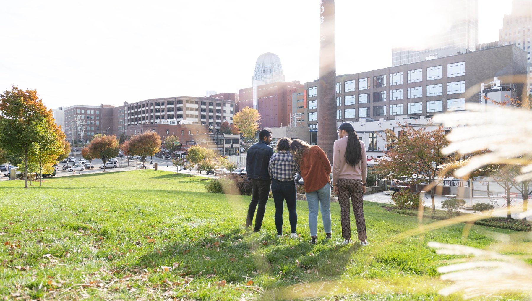 Friends standing in Bailey Park in Winston-Salem admiring fall view of city.