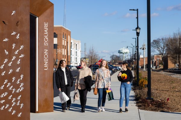 Four women walking on City Walk with shopping bags