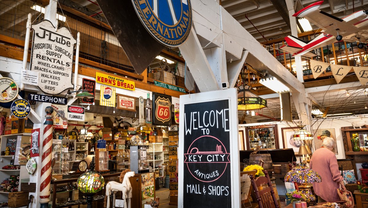 Interior of antique mall, with old signage and knick-knacks and one person shopping.