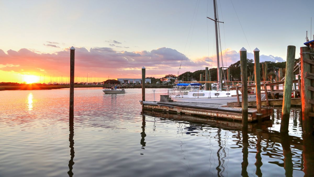 Boats on the water at Southport Yacht Basin with sun rising in distance