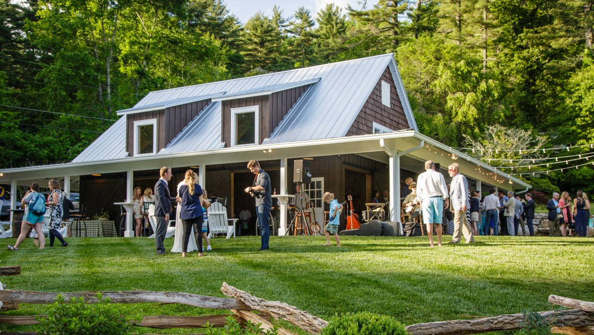 People on lawn of mountain restaurant surrounded by trees during daytime.