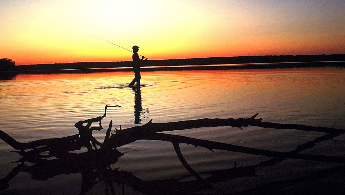 Person fishing against sunrise at Jordan Lake