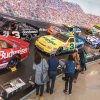 People looking at NASCAR Hall of Fame exhibit with cars on a banked speedway