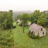 Aerial of of three cabins at Henry River Mill village surrounded by green trees.