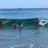 Family of five bodysurfing waves in the ocean during daytime