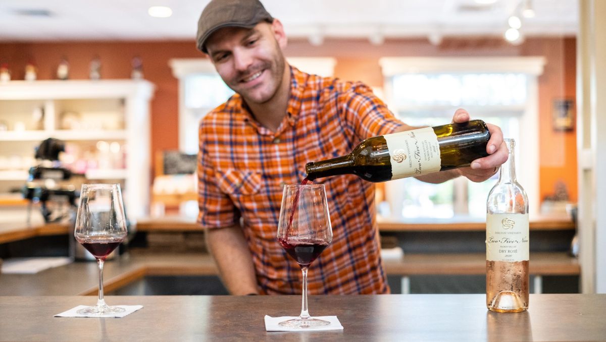 Man pour glass of wine at bar with bottle of wine and glasses on the bar
