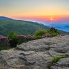 Sun rising over Blue Ridge Mountains with rock and rhododendron in foreground