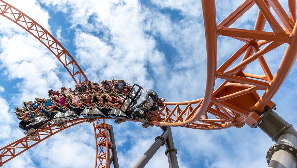 People on rollercoaster with blue sky in background.