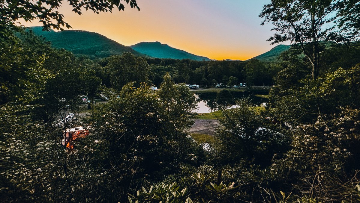 Aerial of Mountain River Family Campground with sun setting over mountains in distance.