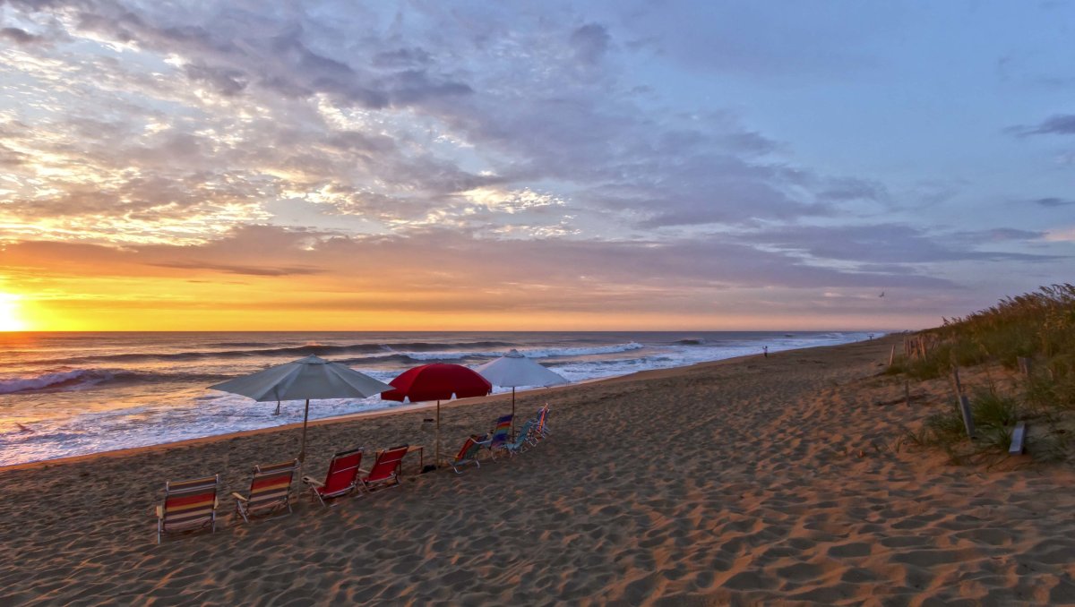 Beach chairs and umbrellas set up on empty beach as sun rises