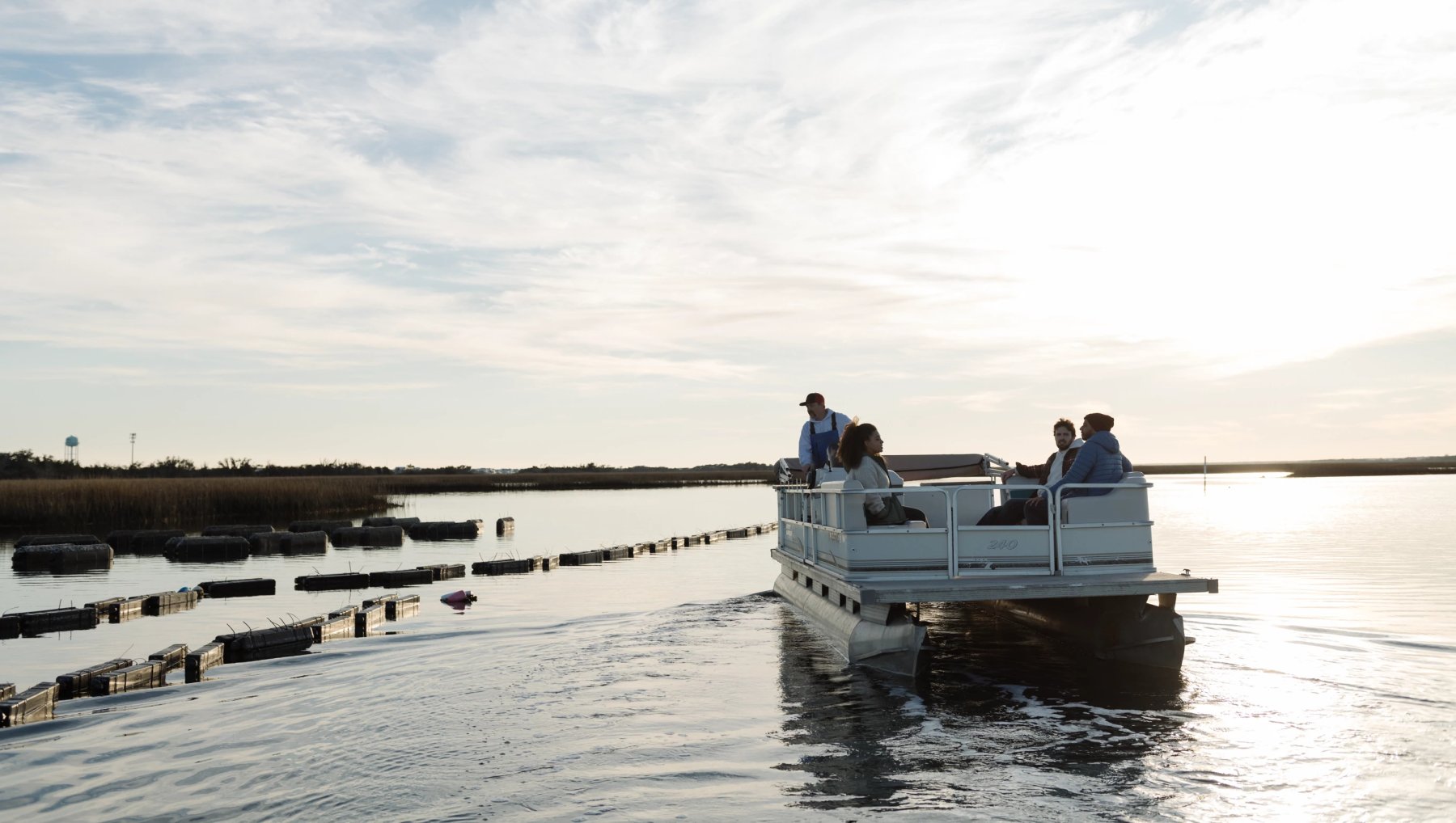 Friends on an oyster tour in quiet sound on clear winter day.