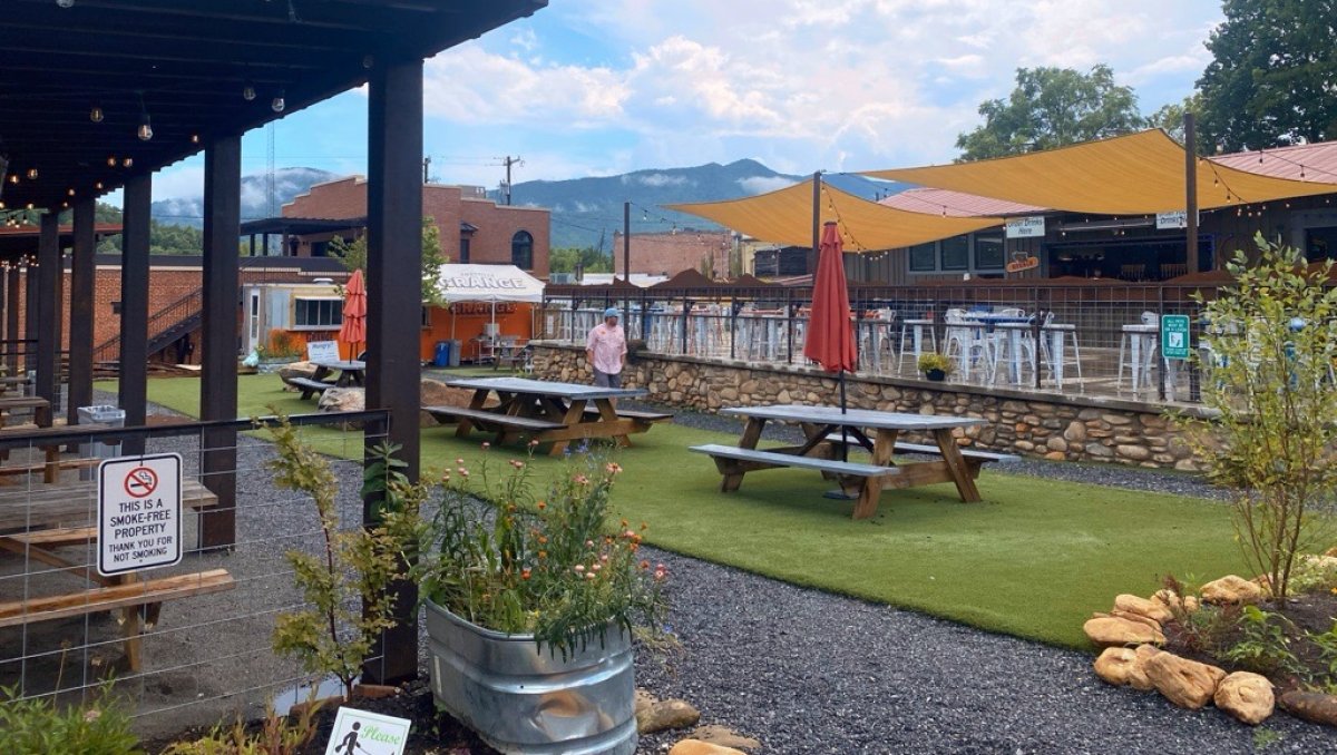 Outdoor beer garden and seating area at Foothills Grange, with mountains in background.