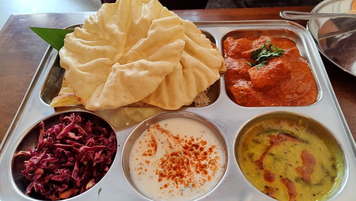 A metal tray featuring an assortment of four different foods, creating a vibrant and inviting culinary presentation.