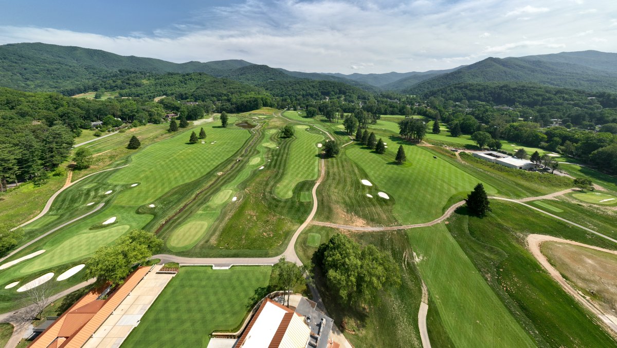 Aerial view of green golf course with mountains in distance during daytime