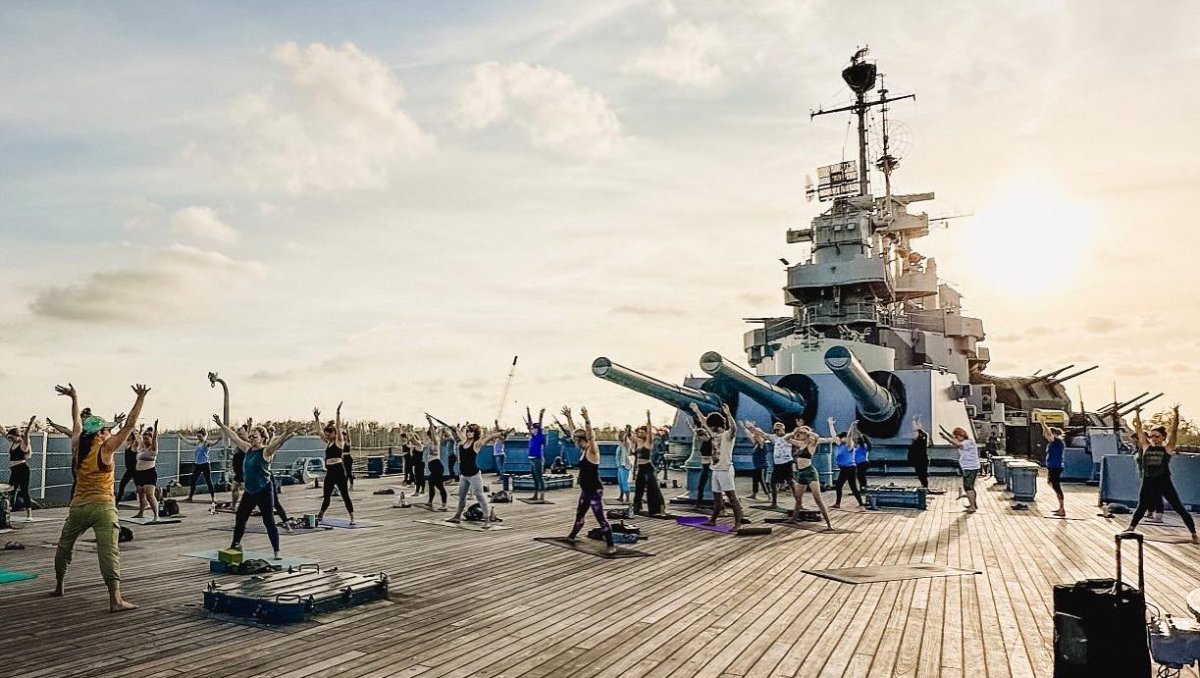 Group of people doing yoga on deck of battleship during daytime