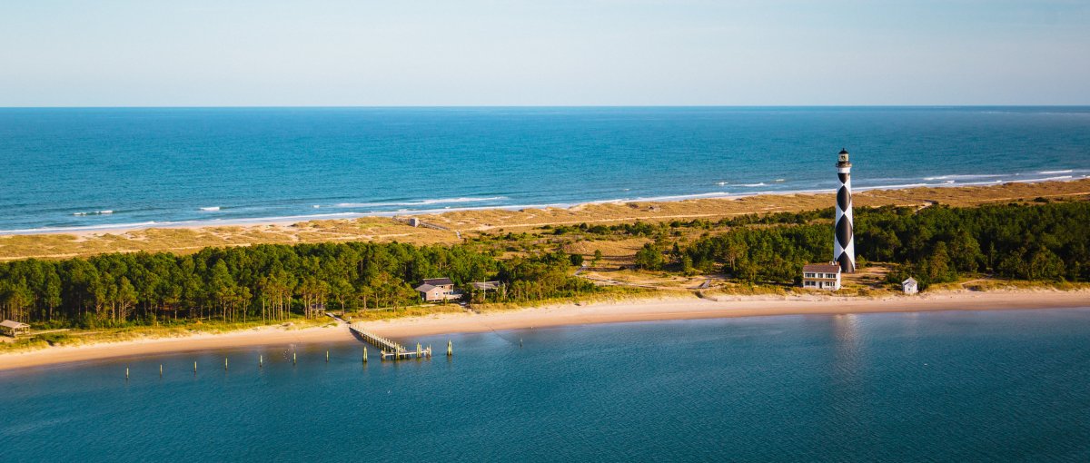 Aerial view of lighthouse, national seashore and water on both sides of land during daytime