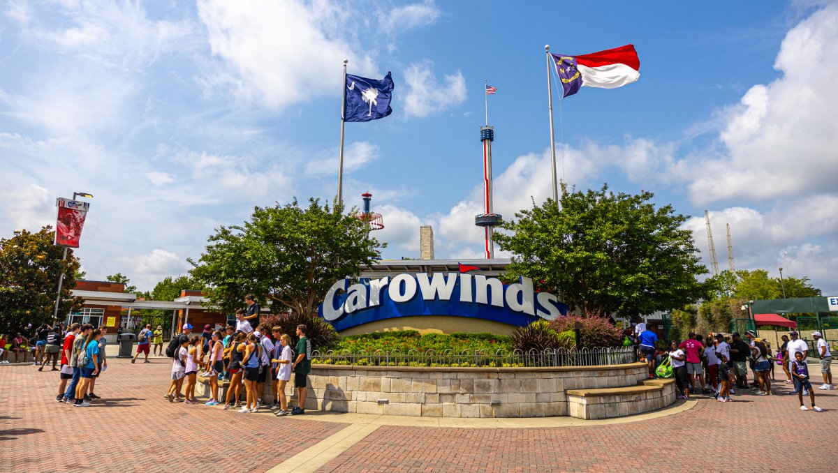 Entrance to Carowinds with large signage and groups of people standing outside.