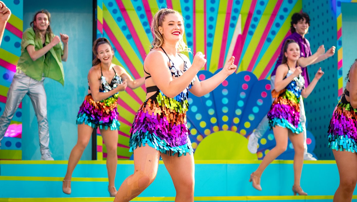 Smiling performers on stage dancing at Carowinds amusement park.