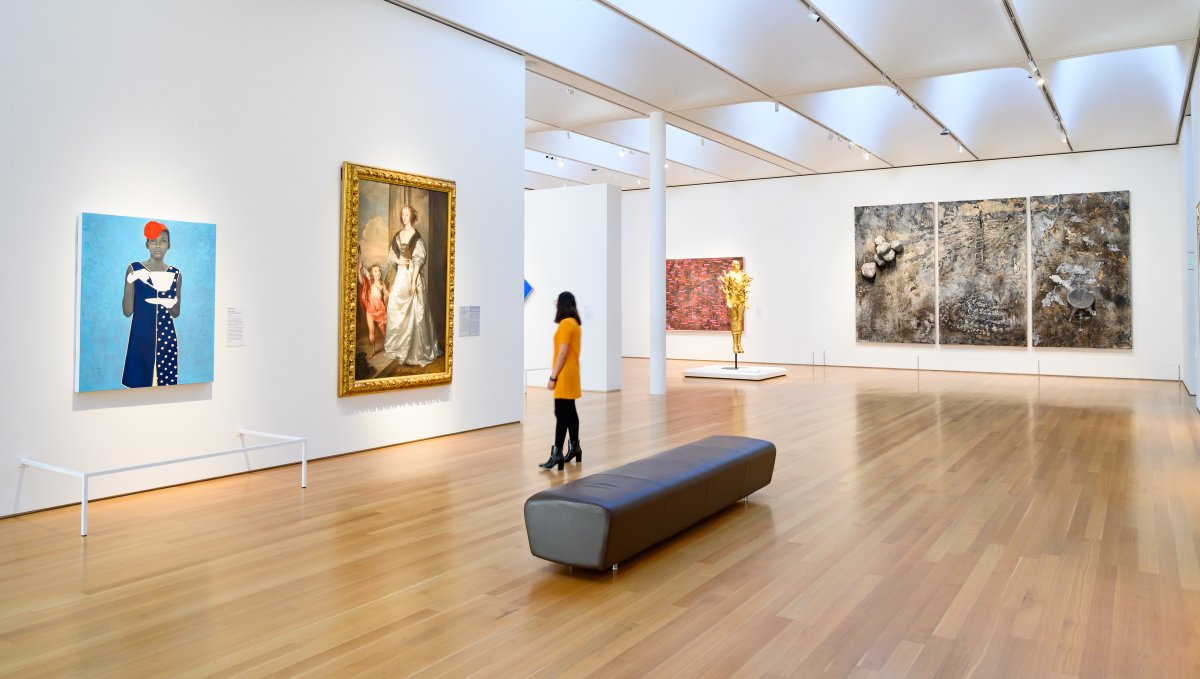 Woman admiring art on walls in large room at NC Museum of Art.