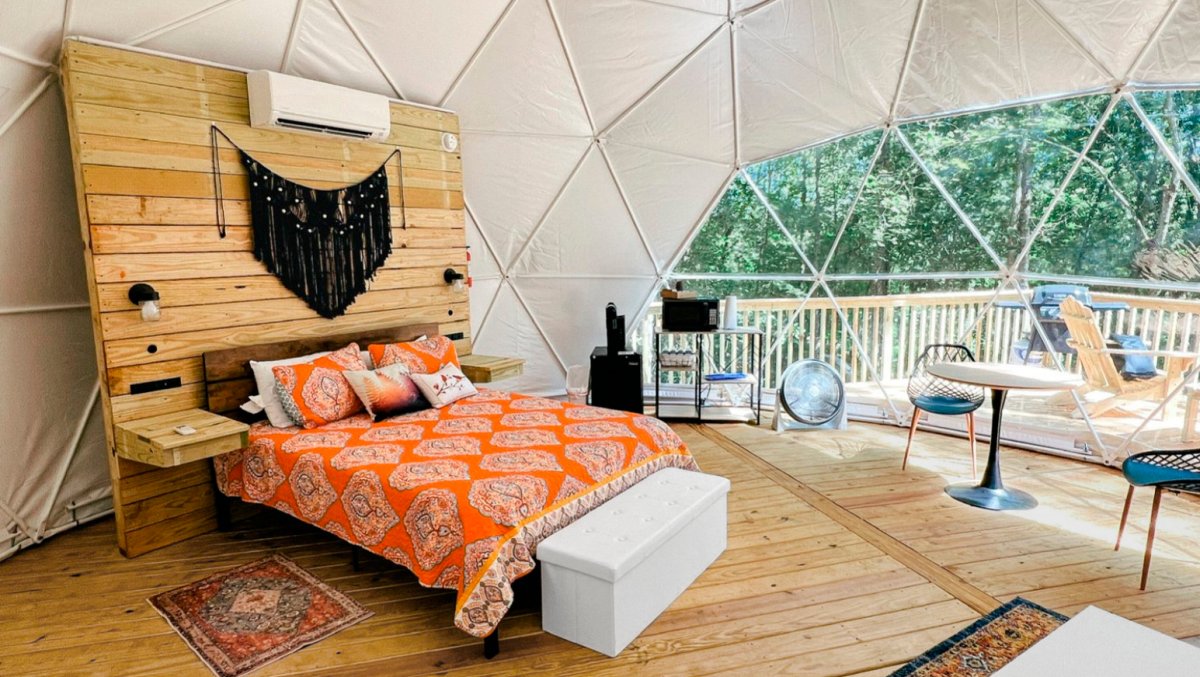 Interior of camping dome with colorful bed and furniture.