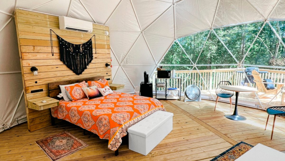 Interior of camping dome with colorful bed and furniture.