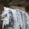 Man ice climbing up waterfall in winter.