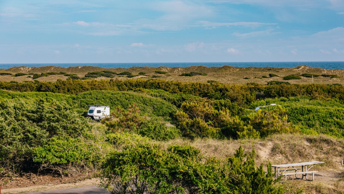 Wide view of Frisco Campground with Atlantic Ocean and dune topography in the background