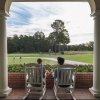 Couple enjoying drinks sitting on rocking chairs overlooking golf course